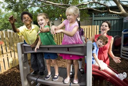 A group of children play together at the top of a play structure at a playground 