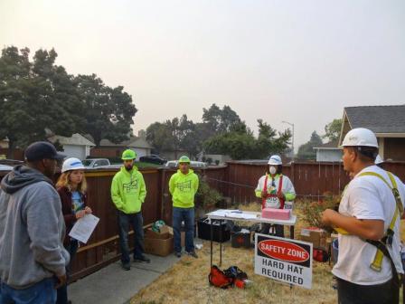 Workers wearing hard hats receiving training at residential property