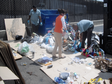 This is a picture of three people going through trash and sorting it into piles.