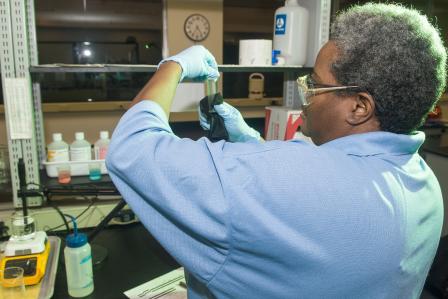 Water treatment plant operator examining a sample in a lab. 