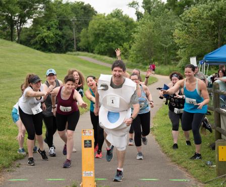 Runners chasing the “running toilet” mascot at the Fix a Leak Family 5k race.