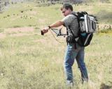 A researcher uses a backpack-mounted spectrometer to sample in a field